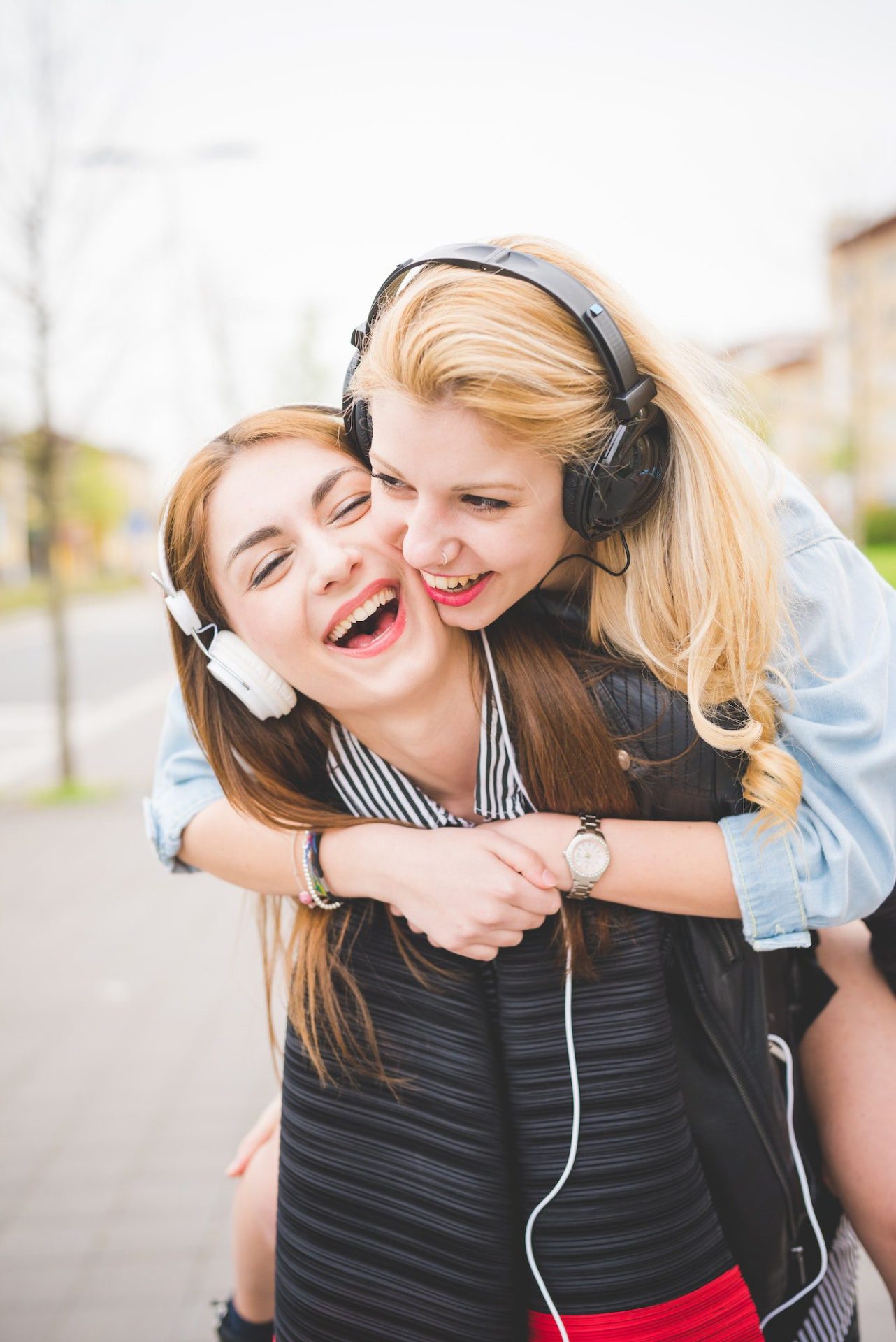 Two young blonde and brunette girls listening to music in the city