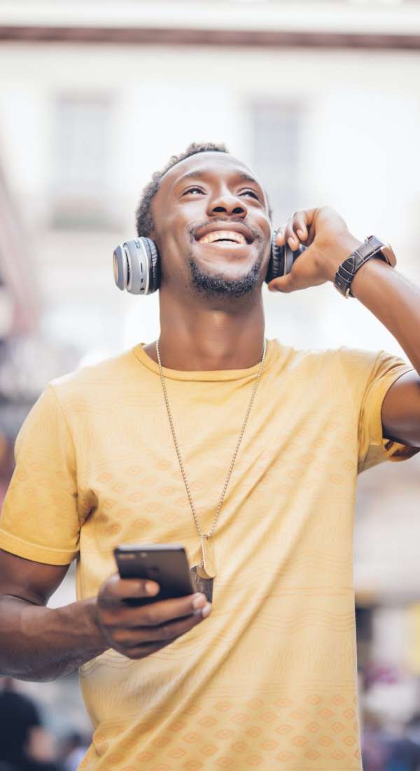 Portrait of happy man listening music with headphones and smartphone